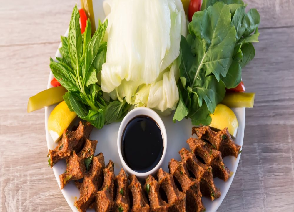 Mevzubahis Çiğköfte oval tabakta yeşillikli çiğköfte sunumu